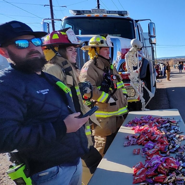 Firefighters standing next to a fire engine during a community event.